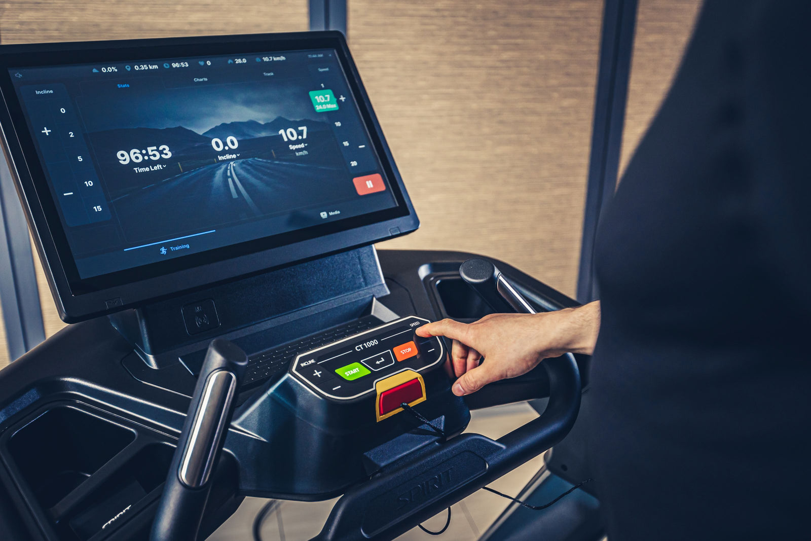 Treadmill control panel with digital display and buttons, showing a person's hand interacting with it.